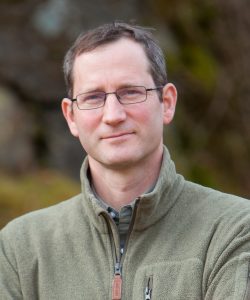 Foto Thomas Hauck. Er trägt einen lodengrünen Fleecepullover und blickt mit einem kleinen Lächeln in die Kamera.