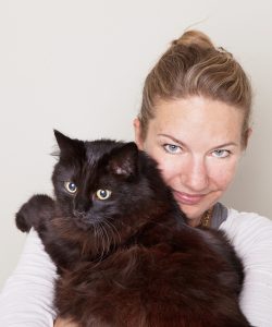 Verena Zimmer hat eine große braunschwarze Katze auf dem Arm.